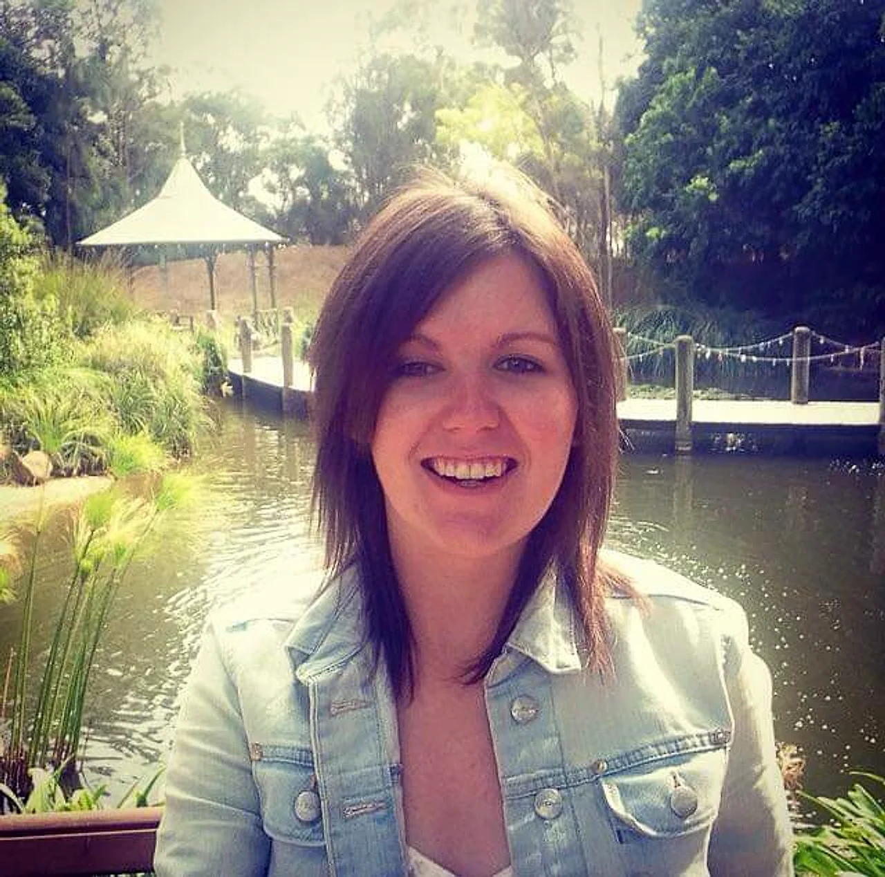 Gemma Gentles smiling in a denim jacket by a lake